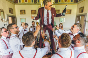 Groom stood on a table surrounded by groomsmen 